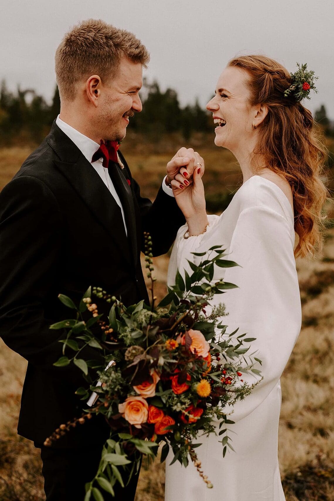 Brudpar håller hand och skrattar.