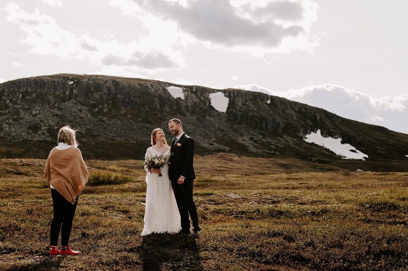 Bröllop i fjällen med brudpar som vigs framför ett berg.
